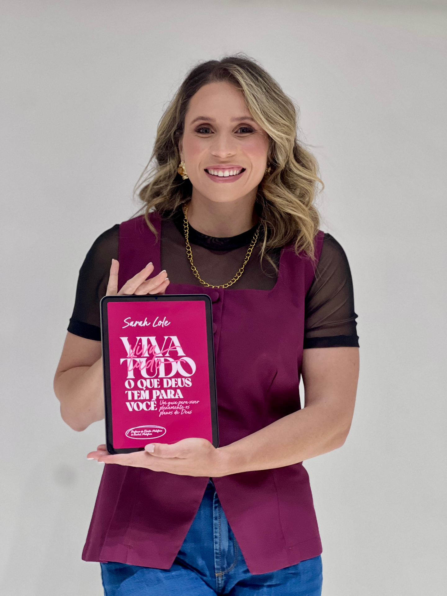 Sarah Lole segurando o e-book Viva Tudo o que Deus Tem para Você
